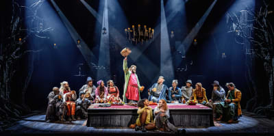 Ett dussintal skådespelare sitter kring ett långbord, klädda som rövarna i Mattisborgen. 