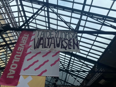 En planch med texten "Tervetuloa taideyliopiston valtaukseen", välkommen till konstuniversitetets ockupation.