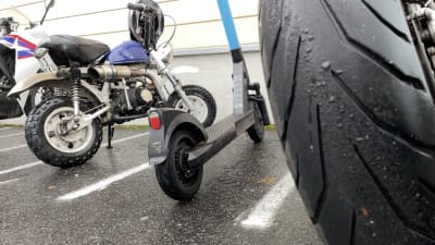 Mopeder och en elskoter står parkerade. 