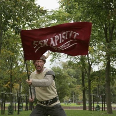 näyttelijä Niko Taskinen puistossa sarvikypärä päässä Eskapistit lippu kädessä