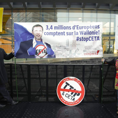Aktivister som motsätter sig frihandelsavtalet Ceta med Kanada, visar upp en banderoll med en bild av premiärminister Paul Magnette och texten "3,4 miljoner europeer litar på Vallonien."