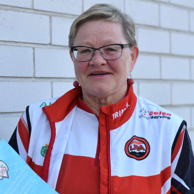 Marja-Liisa Lehto står med Karis Uras 90-års historik i händerna.