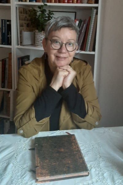 Författaren Ann Holm-Mörn med en gammal bok framför sig.