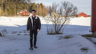 En man som kommer gående. I bakgrunden syns snöiga åkrar och hus.