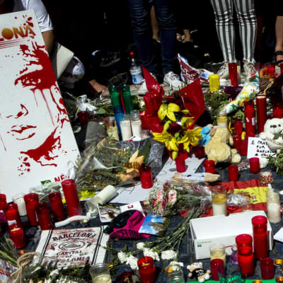 Uhrien muistoksi jätettyjä kynttilöitä ja kukkia sekä kyltti, jossa lukee Rukoilkaa Barcelonan puolesta.