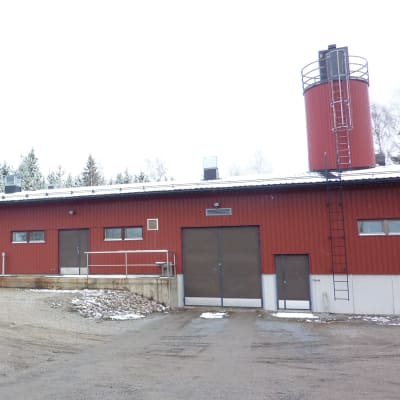 En lång låg röd byggnad.En bil står parkerad utanför. Grått vinterväder, lite snö.