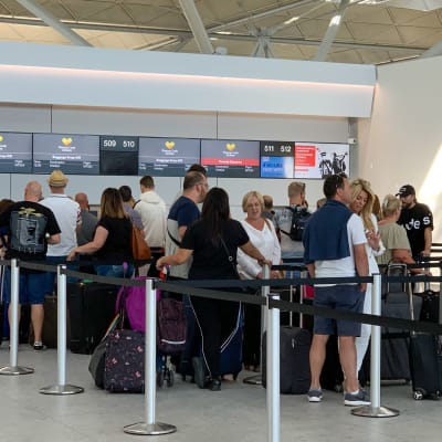 Människor står och köar vid en incheckningsdisk vid flygplatsen Stansted i Storbritannien.