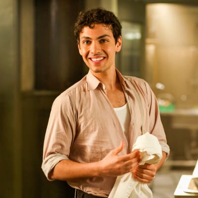 Karaktären Angelo står i köket och torkar sina händer.