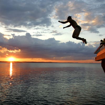 Ung man hoppar i havet