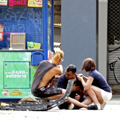 Skadade personer sitter på gatan på La Rambla i centrala Barcelona. 