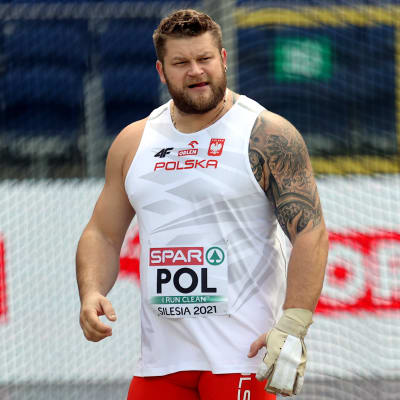 Pawel Fajdek är iklädd en vit tröja med texten POL på en tävlingslapp. 