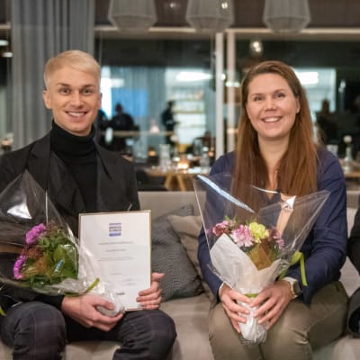Christoffer Strandberg, Satu Österberg och Tom Gammals sitter i en soffa och håller i blommor och diplom.