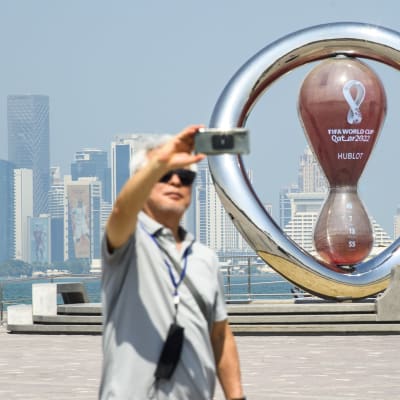 En man tar selfie vid Dohas skyline.