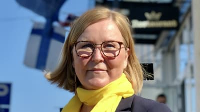 Kaisa Juuso med gul halsduk på Torneå-gata, med Finlands och EU-flagga i bakgrunden