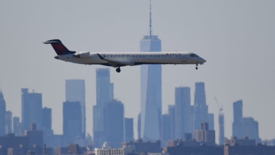 Ett flygplan går in för landning på JFK-flygfältet. I bakgrunden New Yorks disiga skyline
