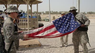Amerikanska soldater viker ihop USA:s flagga i Irak.