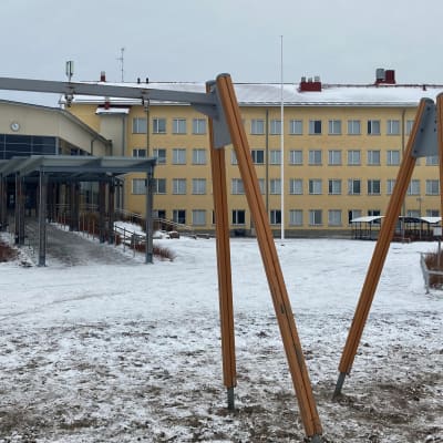 Nelikerroksinen koulurakennus jonka talvinen piha on tyhja-