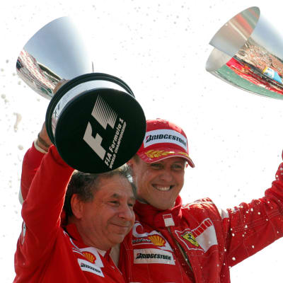 Jean Todt och Michael Schumacher håller om varandra och lyfter varsin pokal.