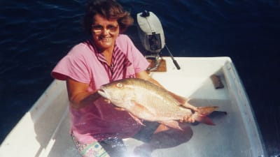 Bild på unga Anneli Sarekoski som fått fisk. Hon sitter i en mindre glasfiberbåt