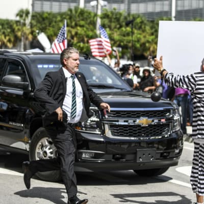 En Trumpmotståndare ställer sig framför Trumps bil när han den förre presidenten lämnar den federala domstolen i Miami.