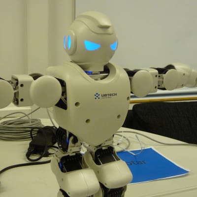 En robot står på ett bord med händerna utsträckta.