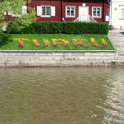 Blomplantering vid åstranden i Åbo med texten Turku Åbo