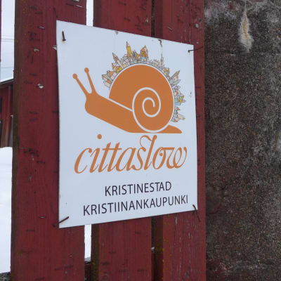 En skylt med bilden av en snigel och under bilden texten "cittaslow kristinestad".