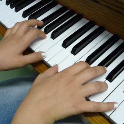 Tangenterna på ett piano, två händer spelar på tangenterna.