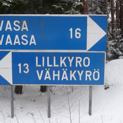 En vägskylt i en korsning i vintertid. Den undre skylten pekar åt höger. På den står det 13 lillkyro. Den övre skylten har texten vasa 16 och pekar åt höger.