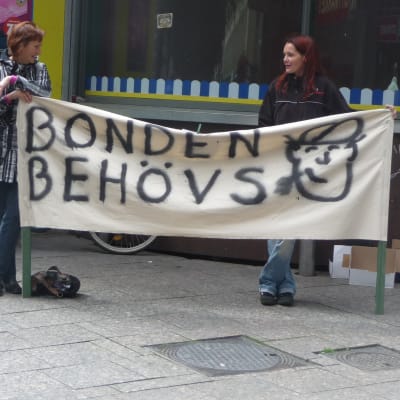 Två kvinnor håller upp en banderoll som lyder "bonden behövs".