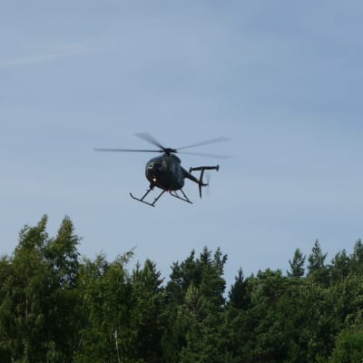 Helikopter flyger ovanför träden.
