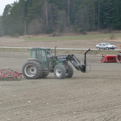 Traktorer på med harv och såmaskin på åkern