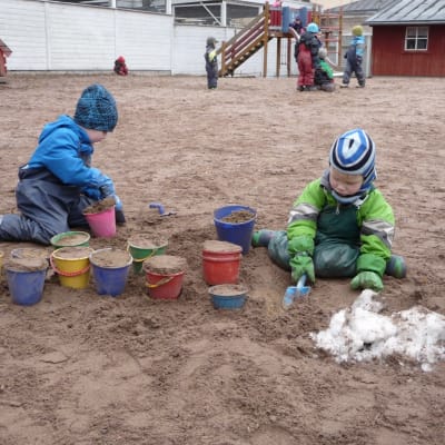 Plasthinkar fyllda med sand, barnhänder som fyller på mera sand.