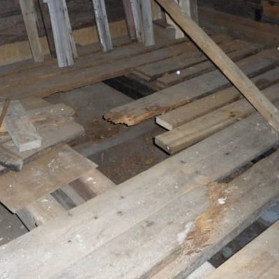 Golvbrädorna, vissa är gamla, vissa är nya. Under golvet syns källarutrymmet.
