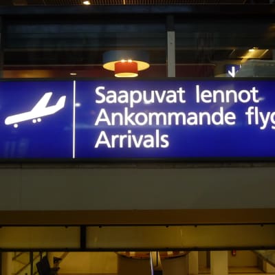 En blå skylt med texten "Ankommande flyg" på finska, svenska och engelska.