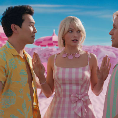 Margot Robbie esittää barbia, ja hän on Simu Liun ja Ryan Goslingin välissä, jotka tuijottavat toisiaan.