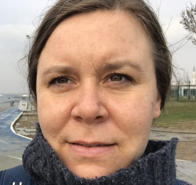 Kvinna utomhus. Ler smått mot kameran.