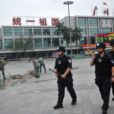 Poliser och städare utanför järnvägsstationen i staden Guangzhou i Kina där 6 personer dödades i en knivattack den 6 maj 2014.