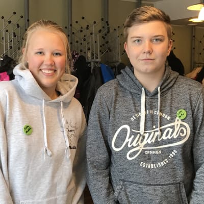 Matilda och Wille i grå tröjor framför garderoben på kulturhuset grand.