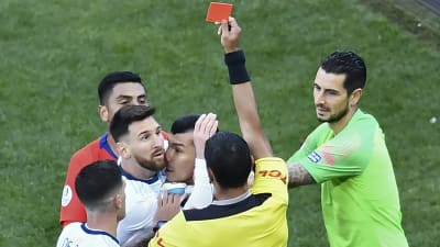 Domaren visar det röda kortet åt Messi, som är mitt i ett gruppbråk.