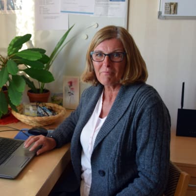 Marianne Löfström-Lahti i Pixneklinikens personalrum. Hon sitter framför en dator vid fönstret.