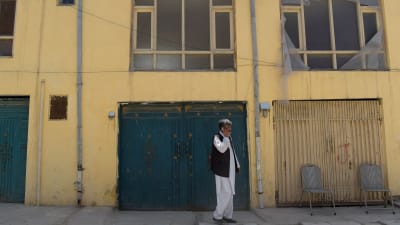 En afghansk man talar i telefon utanför det hus som attackerades i Kabul den 21 maj 2017.  En tyska kvinna och en afghansk vakt dödades medan en finländsk kvinna kidnappades.