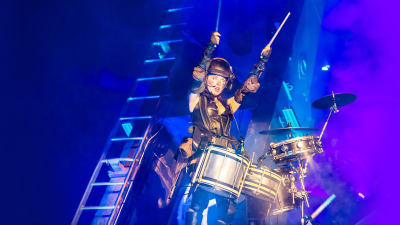Vicky O'neon svävar i luften med trummor live på Glastonburyfestivalen.
