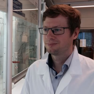 Axel Meierjohann, klädd i en vit labbrock i ett laboratorium.