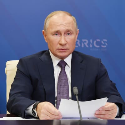 Rysslands president Vladimir Putin sitter vid ett bord med papper framför sig och en blå bakgrund med texten Brics. Putin deltar i Brics-ländernas virtuella toppmöte den 17 november 2020. Brics består av Brasilien, Ryssland, Indien, Kina och Sydafrika.