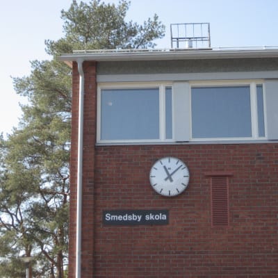 Klocka på skolvägg i rödtegel.