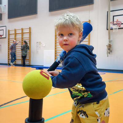 Eljas Tervonen valmistautuu lyömään pehmeällä pesäpallomailalla palloa telineen päästä.