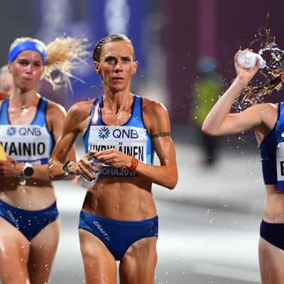 Alisa Vainio, Anne-Mari Hyryläinen och två andra maratonlöpare springer och förser sig med vatten samtidigt.