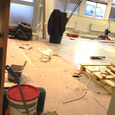 Byggarbetsplats inomhus, kontor byggs om, verktyg och virke på golvet, sopsäckar, papp täcker en del av golvet.