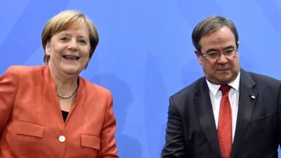 Angela Merkel och Armin Laschet på en presskonfes. Merkel ler medan Armin Laschet tittar ner i podiet.